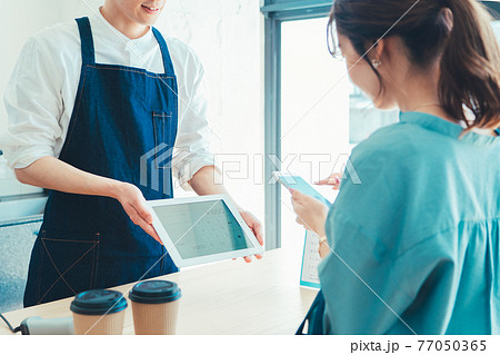 レジでの会計でスマホ決済の準備をする女性 レジでの会計でスマホ決済の準備をする女性 77050365