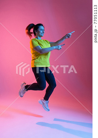 Portrait of beautiful happy woman isolated on pink background in neon light Portrait of beautiful happy woman isolated on pink background in neon light 77051113