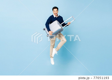 Young energized Asian tourist man with baggage jumping ready to travel Young energized Asian tourist man with baggage jumping ready to travel 77051193