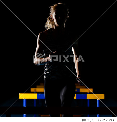 Silhouette of young woman training with hurdles 77052393