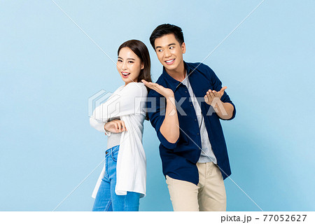 Happy attractive smiling Asian couple on isolated light blue studio background Happy attractive smiling Asian couple on isolated light blue studio background 77052627