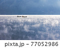 朝靄の幻想的な湖で釣りを行う 77052986
