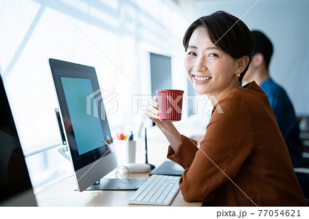 オフィスでコーヒーを飲んでいる女性 77054621