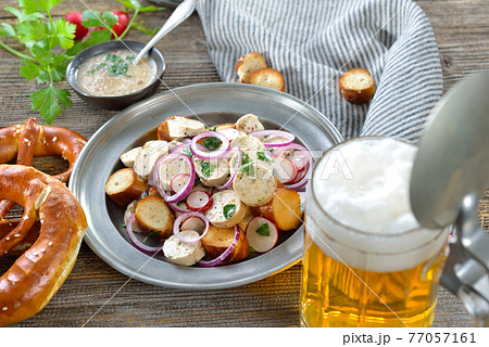 Bavarian beer garden snack with veal sausage salad and pretzels, served with a mug of lager beer 77057161
