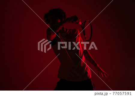 Young caucasian man playing tennis isolated on red studio background in neon, action and motion concept Young caucasian man playing tennis isolated on red studio background in neon, action and motion concept 77057591