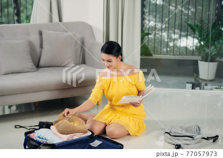 Young woman checking accessories and stuff in luggage Young woman checking accessories and stuff in luggage 77057973