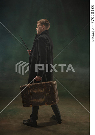 Young man in art action isolated on dark green background. Retro style, comparison of eras concept. 77058136