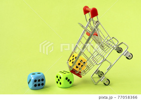 Shopping cart with colorful dice on green background Shopping cart with colorful dice on green background 77058366