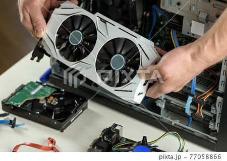 Human hands are inserting a video card into a computer. Human hands are inserting a video card into a computer. 77058866