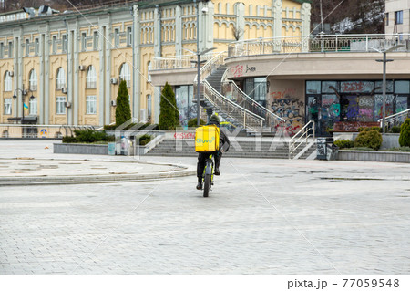 Kyiv, Ukraine - March, 22, 2020: Glovo delivery service courier on an empty Postal Square in Kiev. 77059548