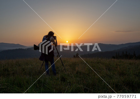 Photographer shoots landscape at sunset 77059771