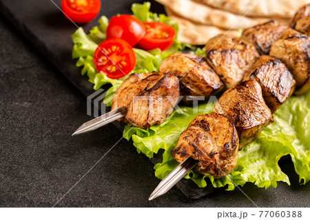 Two portions of shish kebab on a stone plate with salad. Two portions of shish kebab on a stone plate with salad. 77060388