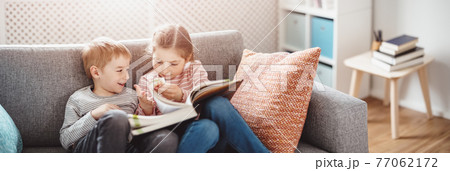 Cute children sitting on the soft sofa and reading books Cute children sitting on the soft sofa and reading books 77062172