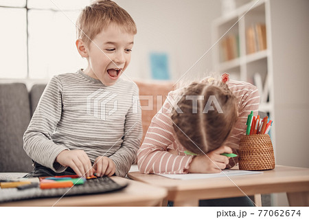 Children sitting on the sofa and playing with modeling clay and with paints. Children sitting on the sofa and playing with modeling clay and with paints. 77062674