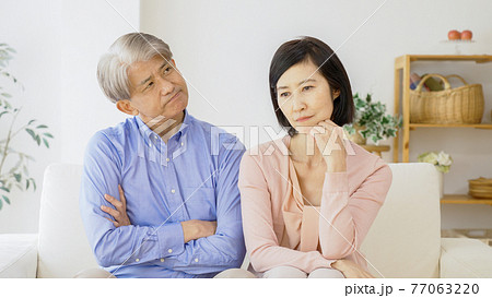 リビングで考え事をする中高年夫婦 リビングで考え事をする中高年夫婦 77063220