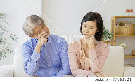 リビングで考え事をする中高年夫婦 リビングで考え事をする中高年夫婦 77063221
