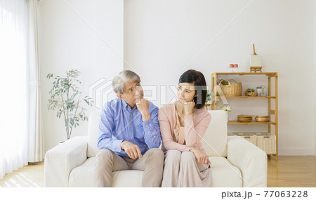 リビングで考え事をする中高年夫婦 77063228