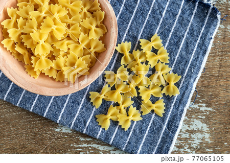 uncooked mini farfalle pasta on rustic background 77065105