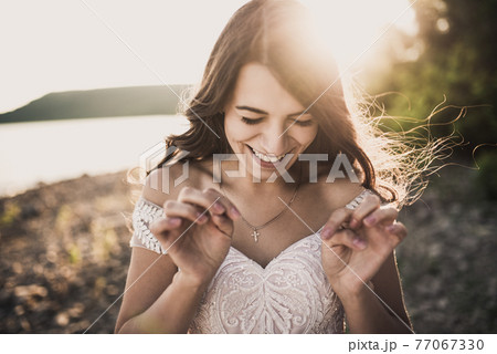 bride in wedding dress happy and laughing against rays setting sun in summer 77067330