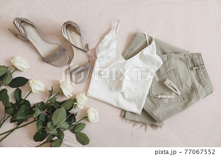 Jeans, sandals and bouquet of flowers on beige background. Top view of female casual spring summer outfit. Trendy stylish women clothes. Flat lay Jeans, sandals and bouquet of flowers on beige background. Top view of female casual spring summer outfit. Trendy stylish women clothes. Flat lay 77067552
