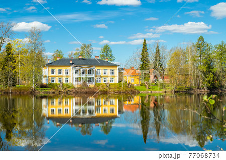Kouvola, Finland - May 16, 2019: Beautiful wooden Rabbelugn Manor - Takamaan Kartano. Wrede family house was built in 1820 on the river Kymijoki bank. Kouvola, Finland - May 16, 2019: Beautiful wooden Rabbelugn Manor - Takamaan Kartano. Wrede family house was built in 1820 on the river Kymijoki bank. 77068734