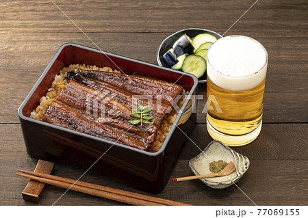 木目のテーブルに置いた照りのある鰻重とビール 77069155