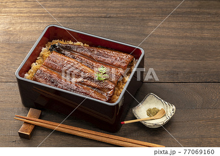 木目のテーブルに置いた照りのある鰻重 77069160
