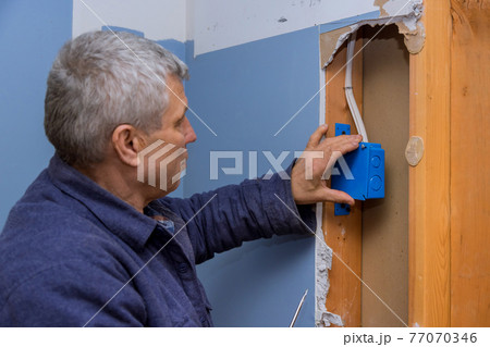 Electrician fasten the electrical box to the beams to place Electrician fasten the electrical box to the beams to place 77070346