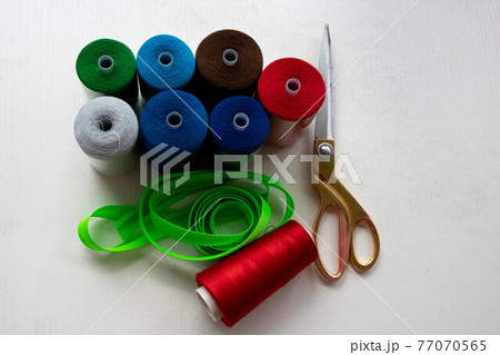 Colorful threads and scissors on a white background 77070565