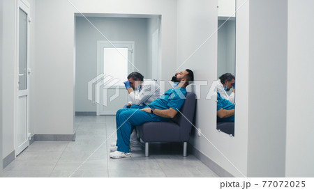 Stressed male doctors sitting on couch in clinic corridor Stressed male doctors sitting on couch in clinic corridor 77072025