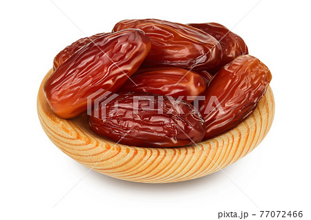 Dates in wooden bowl isolated on white background with clipping path and full depth of field. Dates in wooden bowl isolated on white background with clipping path and full depth of field. 77072466