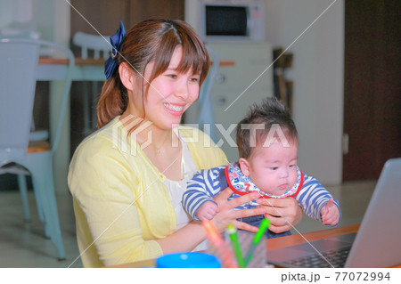 PCに手を伸ばす乳児と笑顔でオンラインミーティングの女性1 PCに手を伸ばす乳児と笑顔でオンラインミーティングの女性1 77072994