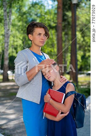 A woman hugs an unhappy schoolgirl daughter A woman hugs an unhappy schoolgirl daughter 77073029