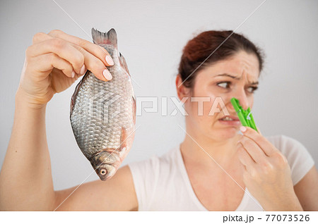 Caucasian woman with a clothespin on her nose because of the disgusting smell of fish. A metaphor for women's health and intimate hygiene. 77073526