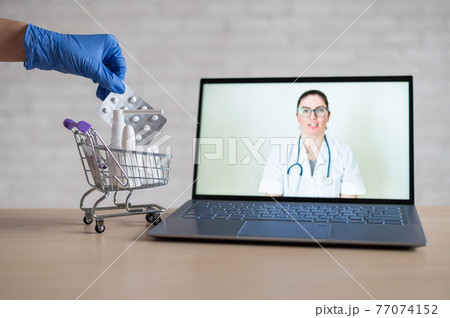 A friendly doctor gives a remote prescription on a laptop. The pharmacist adds a cure for the virus in the mini cart. Online medicine concept. Order drugs online. Video call. A friendly doctor gives a remote prescription on a laptop. The pharmacist adds a cure for the virus in the mini cart. Online medicine concept. Order drugs online. Video call. 77074152
