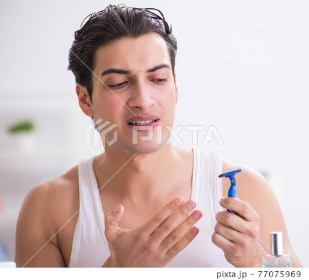 Young handsome man shaving early in the morning at home Young handsome man shaving early in the morning at home 77075969