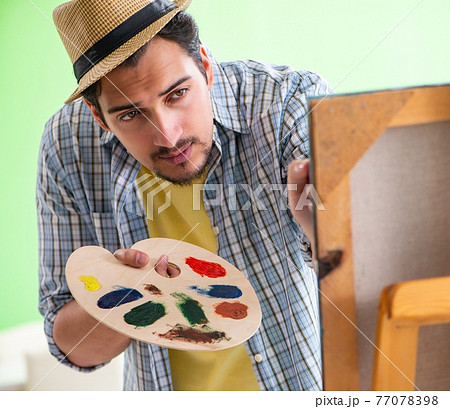 Young male artist working on new painting in his studio 77078398