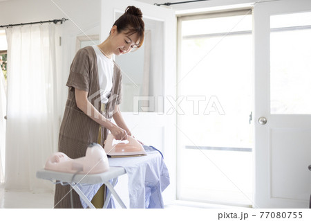 家でアイロンをかける若い女性 77080755