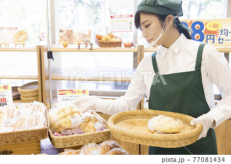 パン屋でパンを並べる従業員女性 パン屋でパンを並べる従業員女性 77081434