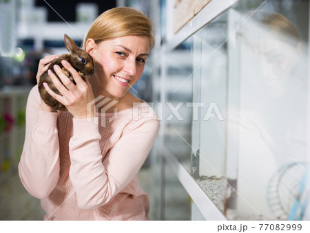 Portrait of woman looking for bunny in pet store Portrait of woman looking for bunny in pet store 77082999