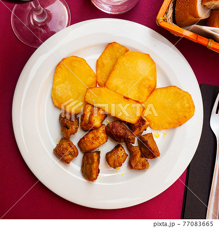 Fried pork meat pieces with baked potatoes 77083665