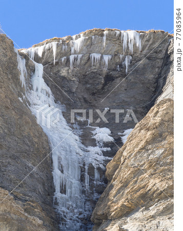 frozen waterfall and ice stalactites on a rock face frozen waterfall and ice stalactites on a rock face 77085964