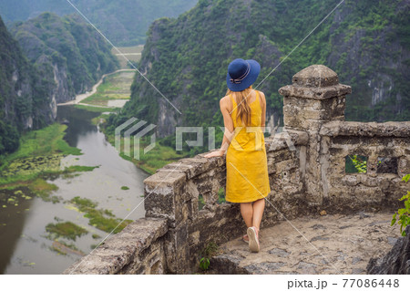 Woman tourist on the lake Tam Coc, Ninh Binh, Viet nam. It's is UNESCO World Heritage Site, renowned for its boat cave tours. It's Halong Bay on land of Vietnam. Vietnam reopens borders after Woman tourist on the lake Tam Coc, Ninh Binh, Viet nam. It's is UNESCO World Heritage Site, renowned for its boat cave tours. It's Halong Bay on land of Vietnam. Vietnam reopens borders after 77086448