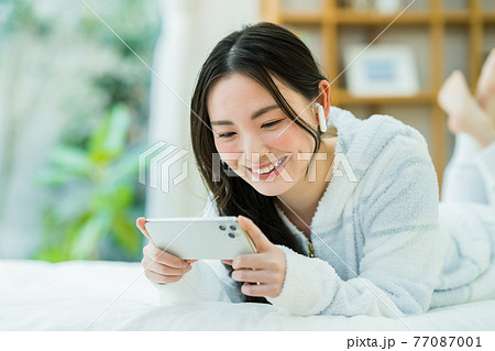 スマホで動画を見る若い女性 スマホで動画を見る若い女性 77087001