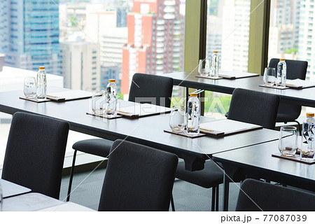 Plastic water bottles, Drinking glasses with pencil and white papers setup on the table prepared for seminar or business meeting in the hotel conference room 77087039