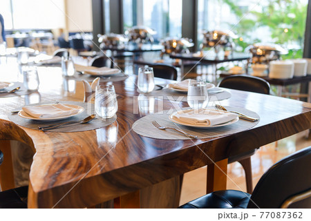 Tableware setting in the restaurant. Decorated elegant table, porcelain plates, glasses, napkin, knife, fork and spoon on wooden table 77087362