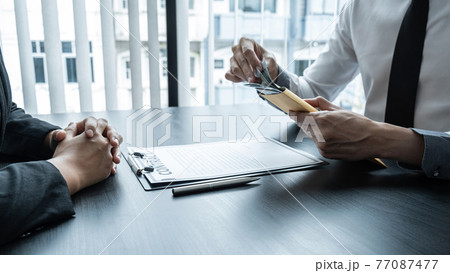 Dishonest cheating in illegal money, Businessman giving bribe money the form of dollar bills to while give success the deal to contract agreement, Bribery and corruption concept 77087477