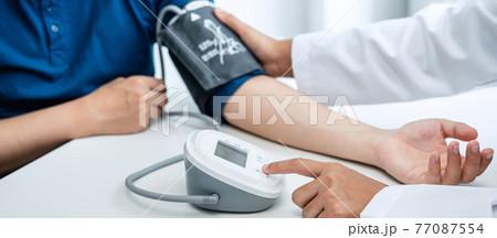 Doctor is checking the patient blood pressure in his hospital office 77087554