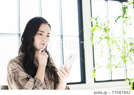 若い女性　スマホ　悩み　困惑 77087842