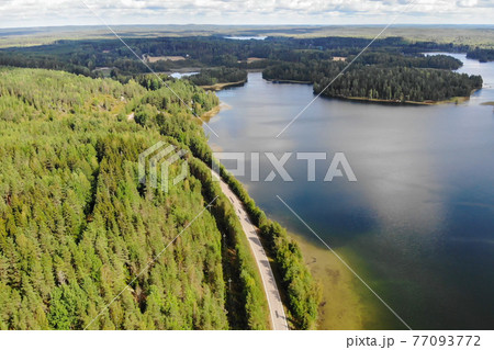 Aerial view of lake with island, road and forest on a summer sunny day in Finland. Drone photography Aerial view of lake with island, road and forest on a summer sunny day in Finland. Drone photography 77093772